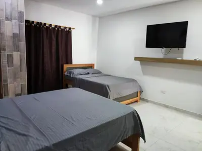 a room with two beds and a flat screen tv at zara's apartamento en coveñas in Coveñas