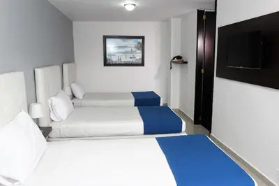 a hotel room with two beds and a flat screen tv at Eslait Hotel & Apartamentos in Barranquilla