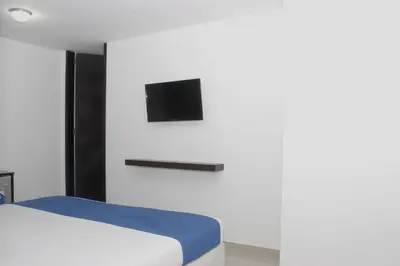 a bedroom with a bed and a tv on the wall at Eslait Hotel & Apartamentos in Barranquilla