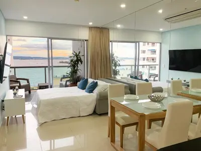 a bedroom with a bed and a living room with a table at Oceanview Escape Pool, Jacuzzi & Gym in Bocagrande in Cartagena de Indias