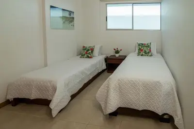 two beds in a room with white walls and a window at Magico Apartamento Frente al Mar 3 Habitaciones PAZ151 in Coveñitas
