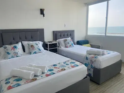 two beds in a room with the ocean in the background at Vista al Mar Fragata Style in Cartagena de Indias