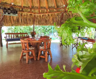 a dining room with a table and chairs and a straw umbrella at Portoazul Casa de Playa in Puerto Colombia