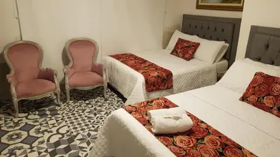 a hotel room with two beds and two chairs at Hotel CastilloMar in Cartagena de Indias