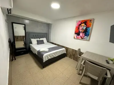 a bedroom with a bed and a table and a desk at Hotel CastilloMar in Cartagena de Indias