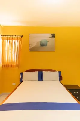 a bedroom with a bed with a yellow wall at Hotel Costa mar in Barranquilla