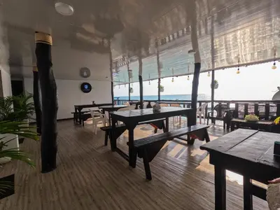 a restaurant with tables and benches and a view of the ocean at Gafitas in Playa Blanca