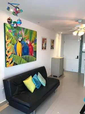 a living room with a couch and a painting of parrots at Hermoso apartamento con vista al mar in Cartagena de Indias