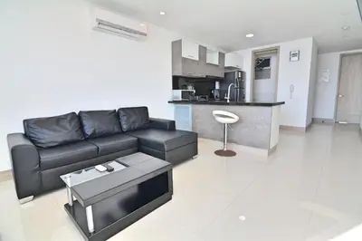 a living room with a black couch and a kitchen at Toscana Suite 2205 in Cartagena de Indias