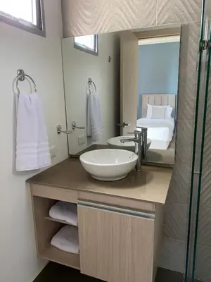 a bathroom with a sink and a mirror and a bed at BUENAVISTA PLAZA APARTA HOTEL in Barranquilla