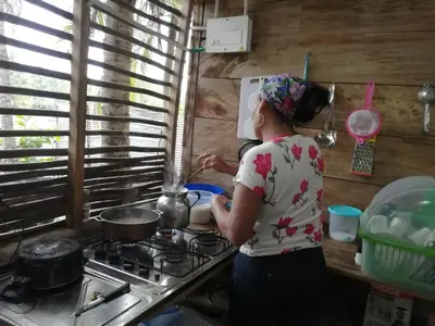 a woman standing in a kitchen preparing food on a stove at LA GAITERA Cabaña in Moñitos