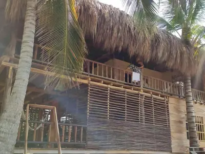 a man sitting on the balcony of a straw hut at LA GAITERA Cabaña in Moñitos