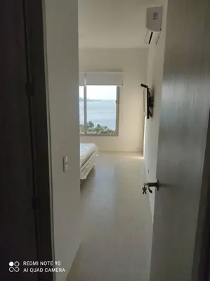 a door leading to a room with a bed and a window at Edificio Sierra Beach Resort Pozos Colorados vista y salida al mar in Santa Marta
