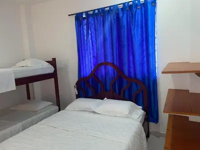 a bedroom with two beds and a blue curtain at Habitacion Playa Linda 102 in Coveñas