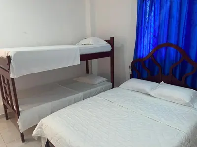 a bedroom with two bunk beds and a blue curtain at Habitacion Playa Linda 102 in Coveñas