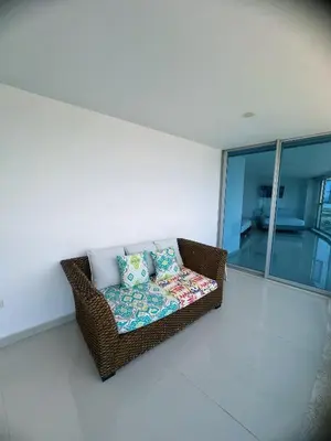 a wicker couch with pillows sitting in a room at Pent House 450 mts 360 front ocean view playa azul in Cartagena de Indias