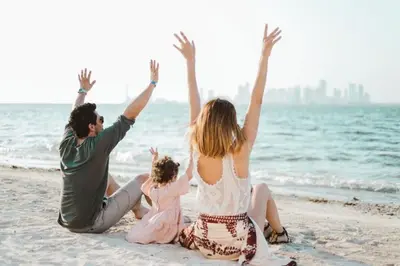 a family sitting on the beach with their hands in the air at Fenix Beach Cartagena in Tierra Bomba