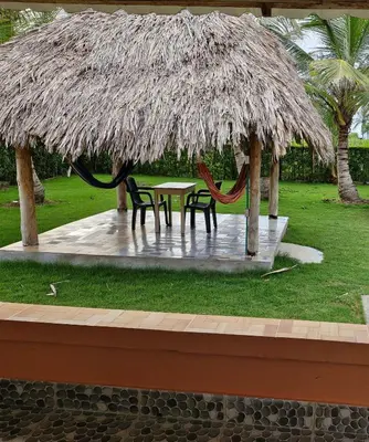 a table and chairs under a large straw umbrella at El ensueño in San Bernardo del Viento
