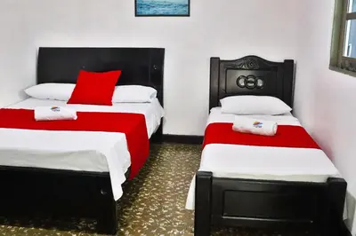 a bedroom with two beds with red and white sheets at Casa Hotel Las Antillas in Tolú