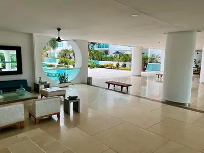 a lobby with tables and chairs and a pool at Edificio con piscina frente al mar con Excelente ubicación piso 4 in Cartagena de Indias