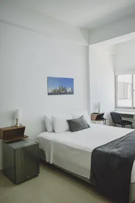 a white bedroom with a bed and a table at Hotel El Marqués De Manga in Cartagena de Indias