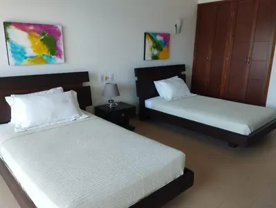 a bedroom with two beds and a night stand with two lamps at Casa Arcoíris: Espectacular casa en Cartagena con Acceso directo a la Playa in Cartagena de Indias