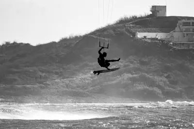 a man in the air on a surfboard in the water at KokohauBungalows in Santa Veronica
