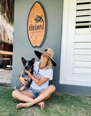 a woman sitting on the ground with a dog at KokohauBungalows in Santa Veronica