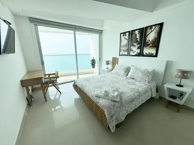 a white bedroom with a bed and a large window at APARTAMENTO PALMETTO ELIPTIC Bocagrande in Cartagena de Indias