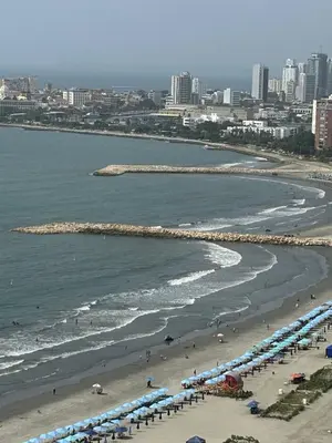 a beach with people and umbrellas and the ocean at APARTAMENTO PALMETTO ELIPTIC Bocagrande in Cartagena de Indias