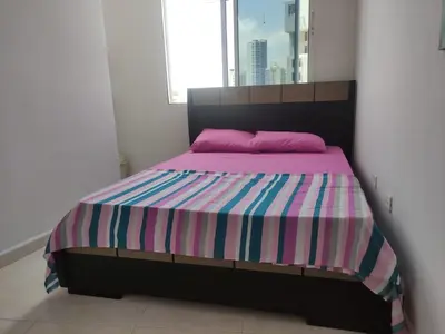a bedroom with a bed with a colorful striped blanket at DULCE HOGAR in Cartagena de Indias