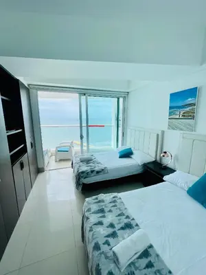 two beds in a room with a view of the ocean at Apartamento Cartagena con vista al mar in Cartagena de Indias