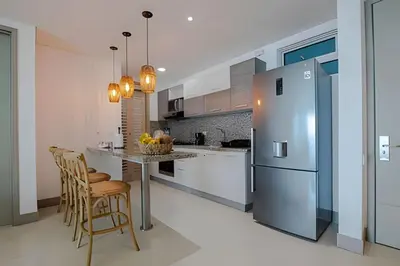a kitchen with a refrigerator and a table with chairs at Laurdhomes Lujoso Apto Piso 28 frente al mar, 2BTH in Cartagena de Indias