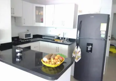 a kitchen with a black refrigerator and a bowl of fruit at Apartamento , vista a la ciudad antigua y playa in Cartagena de Indias
