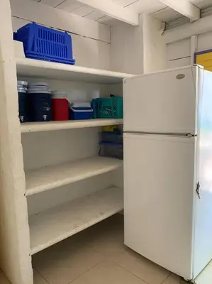 a kitchen with a white refrigerator and shelves at Casita Caribe en reserva natural, playa privada, kayaks, wifi, aire acondicionado in San Onofre