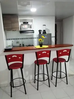 a kitchen with a counter with two red bar stools at Acogedor apartamento en Cartagena in Cartagena de Indias