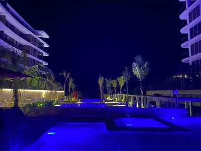a swimming pool at night with palm trees and buildings at Amazing Loft / Private Beach + Pools + Natural in Cartagena de Indias