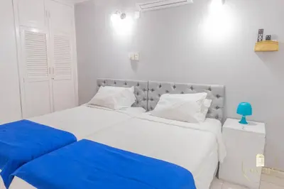 a white bedroom with two beds with blue sheets at Hostal Casa Dandy in Cartagena de Indias