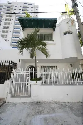 a white house with a white gate and a palm tree at Apartamento en Casa Dandy in Cartagena de Indias