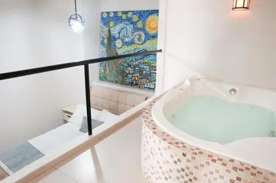a bathtub in a bathroom with a painting on the wall at Casa Badillo 3 4br LUXURY ROOFTOP oldcity AC jacuzzi hottub wifi in Cartagena de Indias