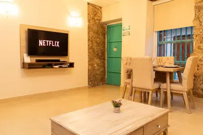 a living room with a table and a television on a wall at Casa Quero 914, 3br Old city wifi jacuzzi in Cartagena de Indias