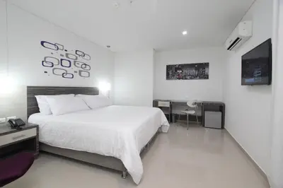 a white bedroom with a large bed and a desk at Hotel Oxford Barranquilla in Barranquilla