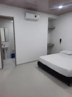 a bedroom with a large white bed and a mirror at HOTEL MAR DEL CARIBE in Soledad