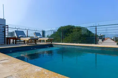 a swimming pool with two chairs and a table at Del Mar Guest House in Cartagena de Indias