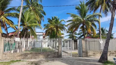 a white fence with palm trees in front of a house at Cabaña 8 Arrecifes in Coveñas