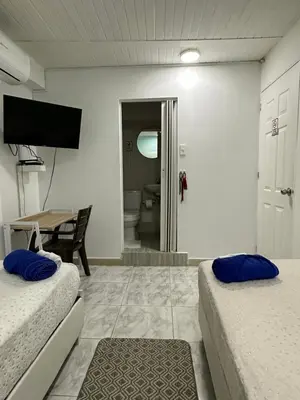 a room with two beds and a table and a television at Casa Cielo Cartagena in Cartagena de Indias