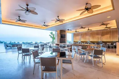 a restaurant with tables and chairs with the ocean in the background at Hilton Santa Marta in Santa Marta