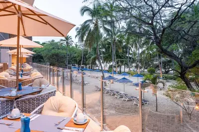 a row of tables and chairs with umbrellas on a beach at Hilton Santa Marta in Santa Marta