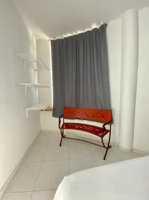 a red bench in a room with a window at Casa Amarilla in Santa Veronica