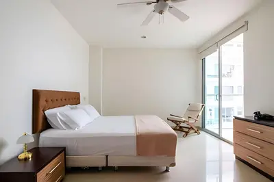 a bedroom with a bed and a chair and a window at Apartamento 1 Dormitorio Morros. Vista Mar Piscina in Cartagena de Indias
